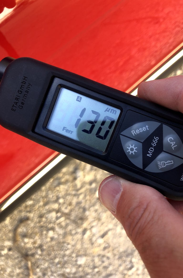 A paint density gauge in front of a red car